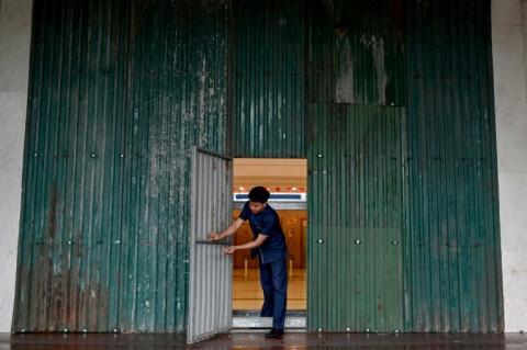 A staff member opens a hotel's door that has been reinforced with corrugated metal sheets before Typhoon Kajiki makes landfall in Vietnam