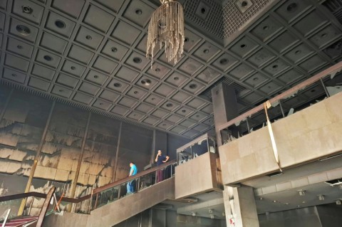 Locals look at the charred remains of the ravaged Parliament building in Kathmandu