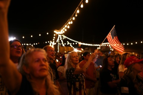 A woman waves a US flag during a candlelight vigil in memory of right-wing activist Charlie Kirk in Morristown, Arizona