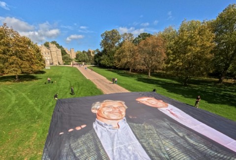 A handout image from the UK collective 'Everyone Hates Elon' shows activists unfurling a large photo depicting US President Donald Trump posing with Jeffrey Epstein, on the Long Walk, outside Windsor Castle in Windsor