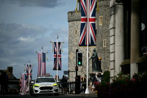 A police car drives past US and Union Jack flags flying from poles outside Windsor Castle