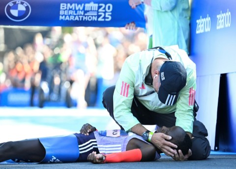Kenya's Rosemary Wanjiru is tended to by a helper, having collapsed after crossing the finish line first.