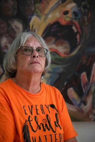 Roberta Hill, residential school survivor from the Mohwak Institute, poses next to a painting by Robert Gary Miller, also a survivor of the Mohawk Institute, during the site's unveiling as a museum in Brantford, Ontario on September 30, 2025