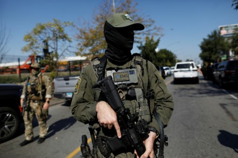 A masked US immigration agent patrols Chicago, where President Donald Trump is also planning to send National Guard troops