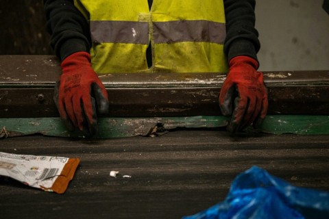 A worker separates plastic objects from other waste on a conveyor belt