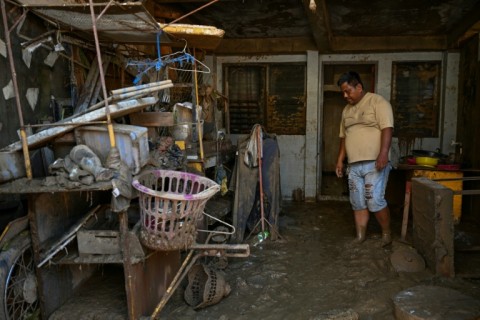 A resident of Cebu province's Liloan town examined belongings covered in mud following the devastation of Typhoon Kalmaegi