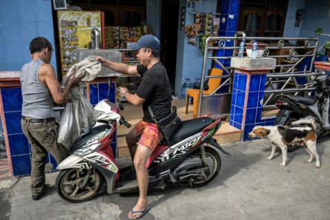 Two men carry a dog in a sack after purchasing it from a vendor before the dog is to be slaughtered and cooked in Jakarta
