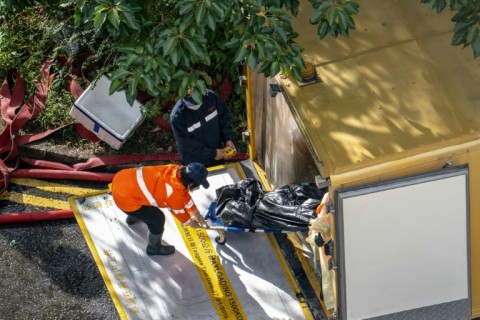 A body is transferred to a vehicle in the aftermath of a major fire that swept through several apartment blocks in Hong Kong