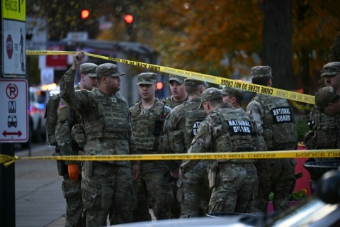 National Guard soldiers stand behind crime scene tape at a corner in downtown Washington where two National Guard soldiers were shot just blocks from the White House