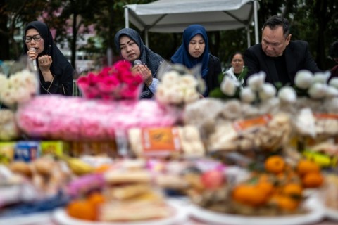 Indonesians pray for victims of the fire, which killed at least nine Indonesians with 42 others unaccounted for