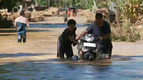 People wade through floodwater on Indonesia's Sumatra as death toll rises to 712