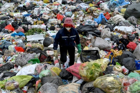 A woman picks up plastic waste at a landfill on the outskirts of Hanoi