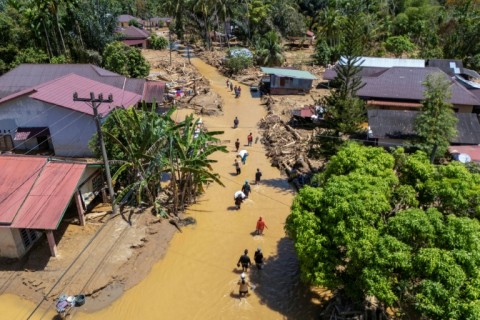 This picture shows an aerial view of villagers wading through the mudflow to find a shelter in the aftermath of flash floods in Tukka village, Central Tapanuli, North Sumatra province, on December 3, 2025