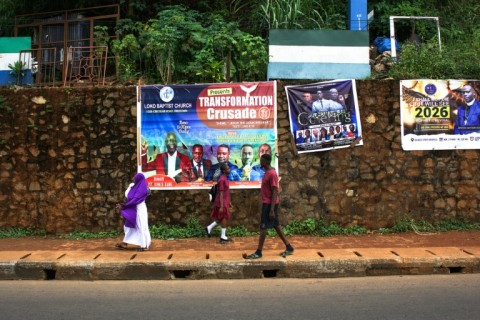 Pedestrians walk past different religious banners in Freetown, Sierra Leone in November 2025