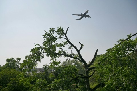 A commercial aircraft flies over the accident site of the Air India crash, still unresolved after six months