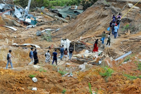 People walk past damaged houses following a landslide in Ulapane village in Kandy, Sri Lanka