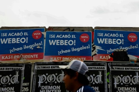 A person walks past posters supporting Chilean presidential candidate Jose Antonio Kast of the Republican Party in Santiago