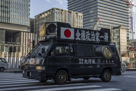A van of the ultra-nationalist group Taikosha emblazoned with 'Wipe out money-driven politicians' drives near Tokyo station