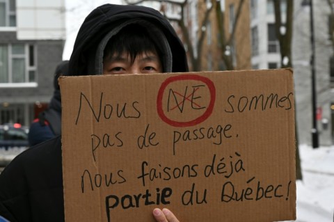 A pro-immigration demonstrator in Montreal, Canada holds a sign that reads in French: 'We're not just passing through, we're already part of Quebec'