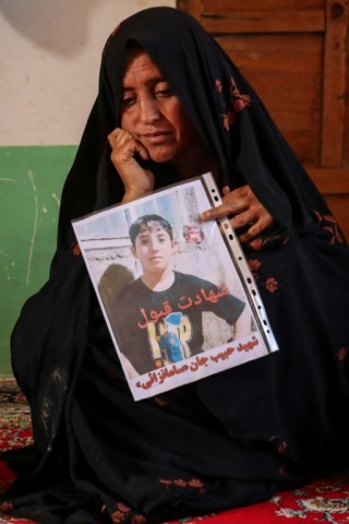 Mah Jan holds a picture of her deceased son, Habibullah, at her house in Ghunjan village. Iran and Pakistan have combined sent back five million Afghans since September 2023