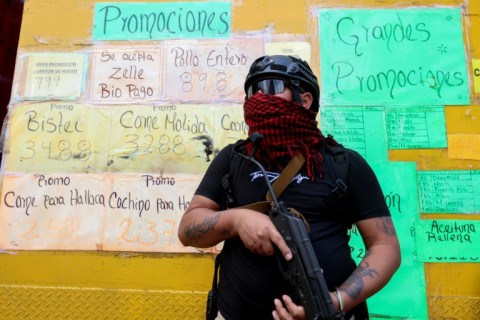 An armed supporter of ousted Venezuelan President Nicolas Maduro stands guard as he monitors vendors from speculating on goods prices in Caracas