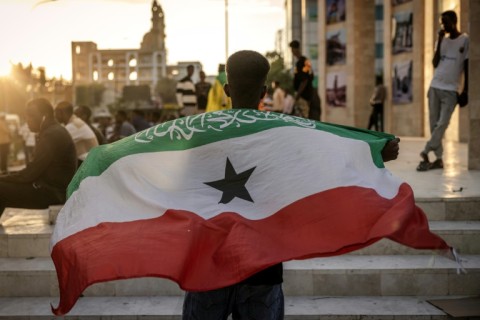 A man holds a flag of Somaliland in front of the Hargeisa War Memorial monument