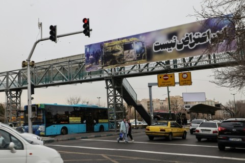 Cars drive under a banner that reads "This is not a protest" in Tehran