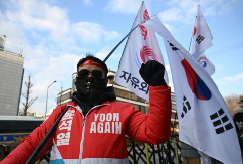 A supporter of South Korea's former impeached president Yoon Suk Yeol carries a large national flag in front of the Seoul Central District Court in Seoul on January 9, 2026