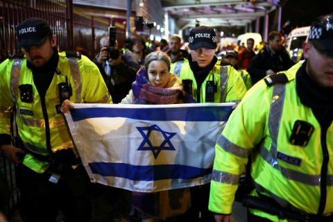 Police officers escort a woman with an Israeli flag away from Pro-Palestinian protesters outside Villa Park in Birmingham on November 6, 2025 ahead of the UEFA Europa League league-stage football match between Aston Villa and Maccabi Tel Aviv