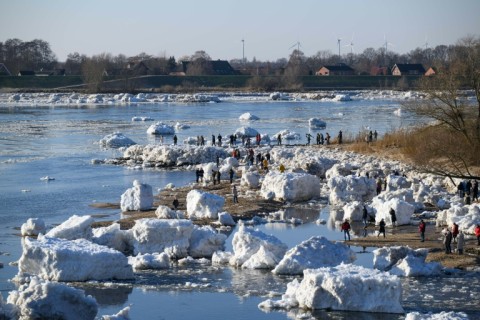 Onlookers make their way through large chunks of ice washed up along the banks of the Elbe river near Geesthacht, northern Germany, on January 19, 2026.