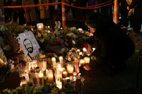 A woman lights a candle while mourning at a memorial where Alex Pretti was shot dead by federal immigration agents in Minneapolis