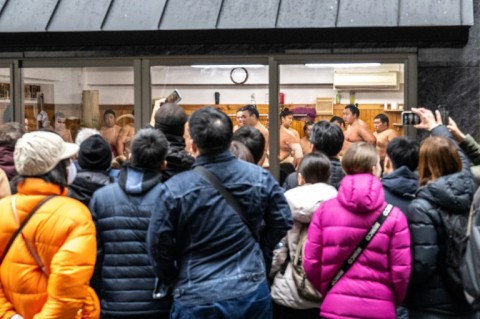 Residents and tourists watch the morning practice from the street in front of the Arashio sumo stable in Tokyo