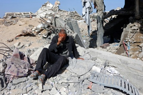 A man sits in the rubble of Sheikh Radwan police station in Gaza City after the Israeli air strike