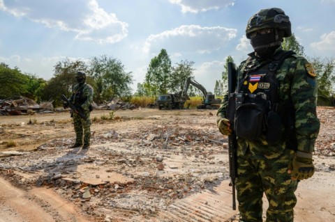 Soldiers stand guard in front of an excavator filling a truck with debris on February 5, 2026 during a military organised tour near Ban Nong Chan, an area now controlled by Thai forces