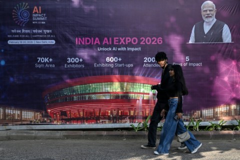 Commuters walk past a billboard for an AI Expo in New Delhi