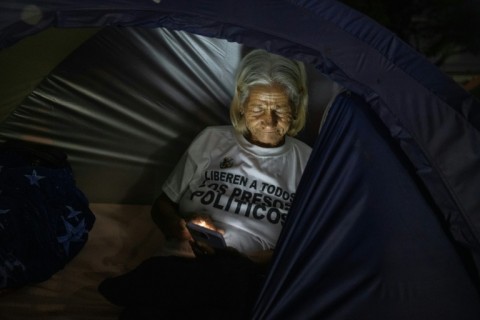 A relative of a political prisoner watches a livestream of lawmakers debating an amnesty bill, in her tent outside Rodeo I prison, on February 19