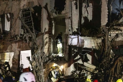 Israeli security forces inspect the site of an Iranian missile strike in Tel Aviv