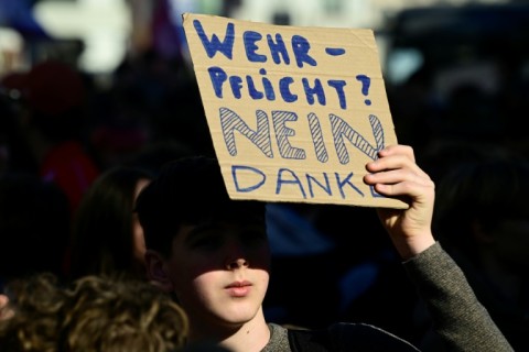 A student holds a sign reading 'Military conscription? No thanks'