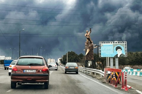 Plumes of black smoke mix with rain clouds in the skies of Tehran