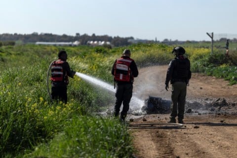 Israeli firefighters extinguish debris from a missile that landed in an open field near the city of Ashdod on Sunday