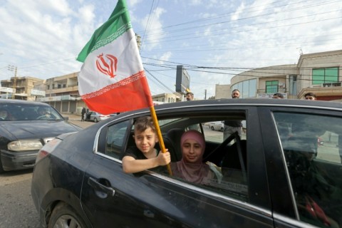A boy holds Lebanon's flag as his family returns to the south of the country after a 10-day ceasefire deal came into force