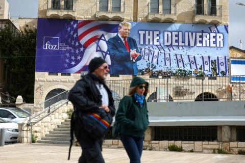 People walk past a banner depicting US President Donald Trump in Jerusalem