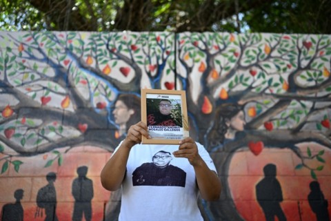 Esmeralda Rosales shows a portrait of her missing brother, Fernando Rosales, during the inauguration of a mural in tribute to disappeared people, at the University of El Salvador, in San Salvador, on March 19, 2026