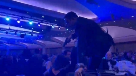 An armed agent climbing over chairs as they move to the stage after loud bangs were heard during the White House Correspondents' dinner