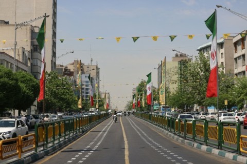 Vehicles drive along a street adorned with Iranian flags at Revolution Square in Tehran on Tuesday
