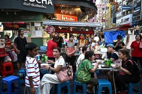 People eat noodles from a street food stall in Chinatown, Bangkok, where for many vendors the steady flow of customers is worth the risk of city fines