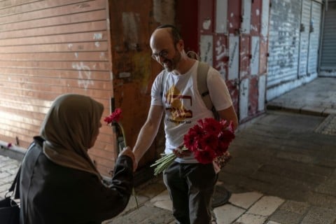 Dozens of Israeli peace activists dressed in white handed flowers to passersby