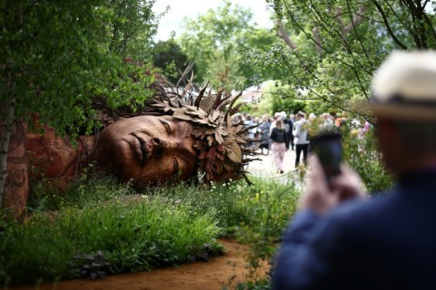 A visitor takes a photo of the Gaia in The Campaign to Protect Rural England's Garden: "On the Edge" at the 2026 RHS Chelsea Flower Show in London