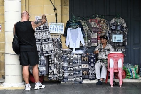 A tourist looks to buy a pair of so-called elephant pants outside the Grand Palace in Bangkok. Shorts are not allowed to be worn on the premises