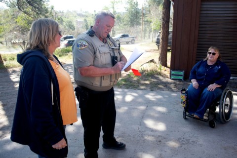 Ouray County sheriff’s Deputy Larry Graves fills out paperwork as residents wait to evacuate during a mock fire evacuation drill in Ouray County, Colorado